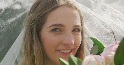 Joyful Bride Smiling Under White Wedding Veil With Blooming Flowers