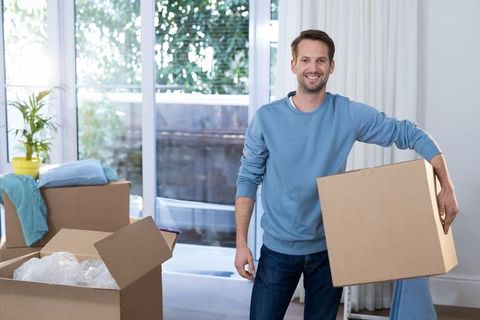 Man Smiling While Holding Moving Box Inside Home