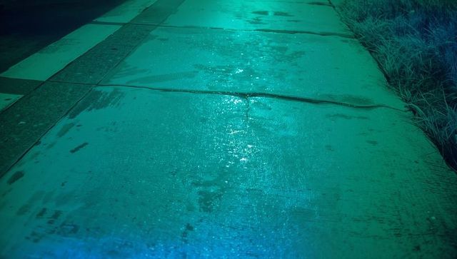 Moody urban night scene with wet concrete sidewalk