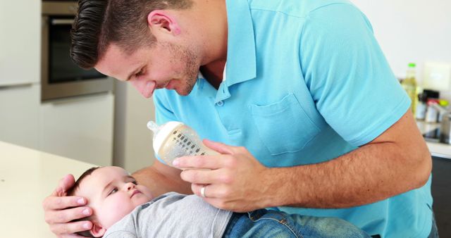 Loving Father Feeding Baby With Bottle in Kitchen - Download Free Stock Images Pikwizard.com