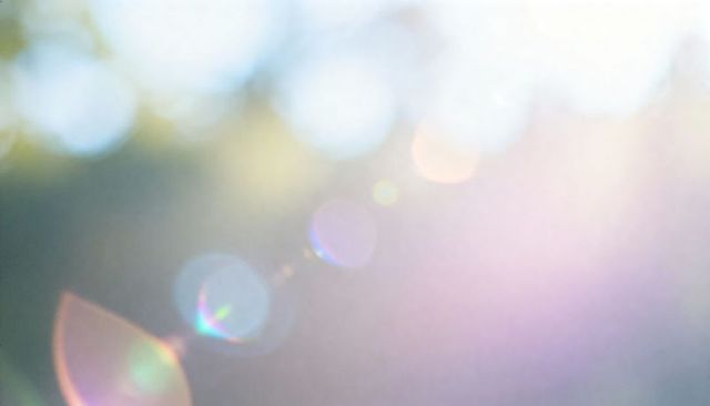 Diagonal sunflare orbs creating pastel bokeh backdrop with soft-focus halos and foliage