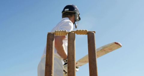 Cricket batsman standing behind stumps wearing helmet and holding bat ready for strike