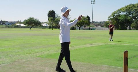 Cricket bowler signaling delivery and walking on practice pitch with wicketkeeper watching