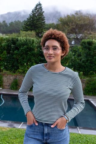 Young woman relaxing in yard with pool and green landscape