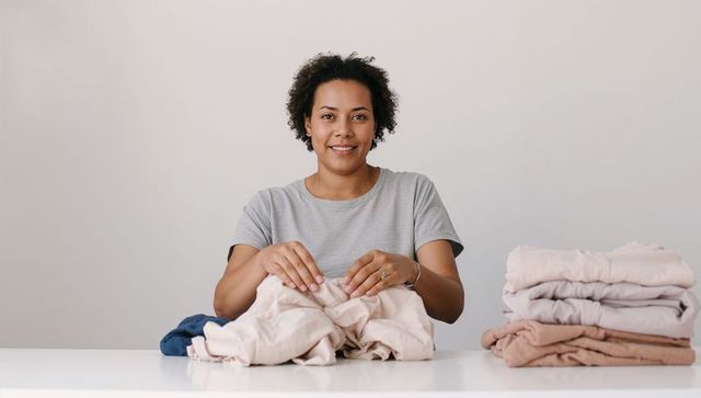 Folding laundry at home with neutral linens, minimalist organization and calm lifestyle