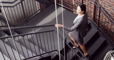 Asian businesswoman climbing industrial stairs to success
