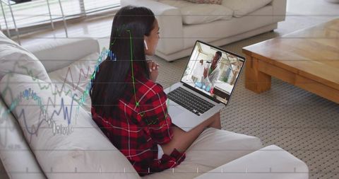 Woman working from home on laptop video call while analyzing financial charts overlay