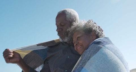 Senior Couple Embracing on Beach Under Blanket