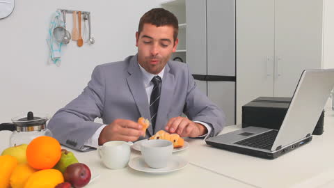 Businessman Having Breakfast While Working on Laptop
