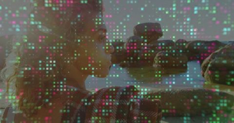 Woman leaning on rock by sea with digital technological overlay