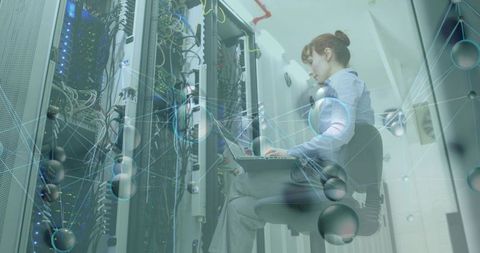 Female IT technician checking servers with laptop in datacenter aisle, network maintenance