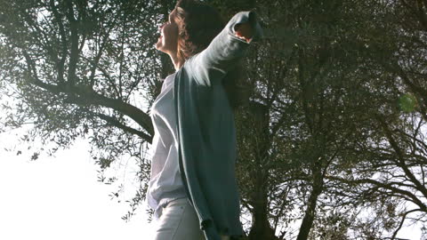 Joyful Woman Twirling Under Sunlit Tree
