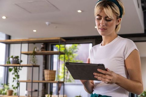 Woman holding tablet wearing headset in modern office environment