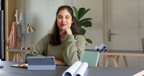 Creative designer woman smiling while sketching plans on tablet in bright home studio