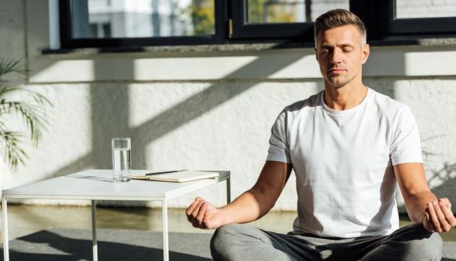 Meditating man embracing mindfulness in sunlit minimal home interior