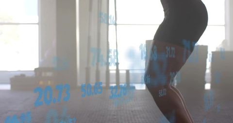 Squatting Athlete Lowering Hips in Gym with Blue Performance Data Overlay and Backlit Silhouette