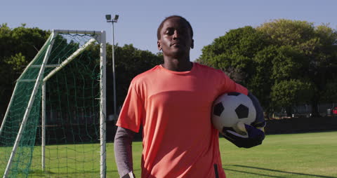 Confident Soccer Player Standing on Field Holding Ball