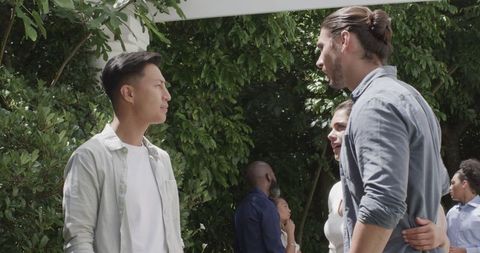 Guests conversing outdoors at sunny wedding celebration