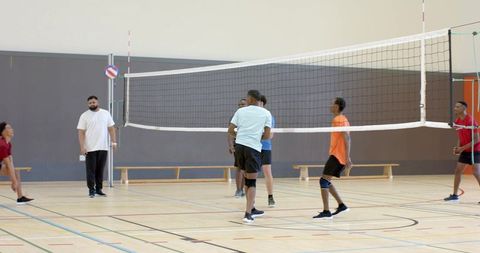 High-energy youth indoor volleyball match showcasing teamwork with colorful ball and coach