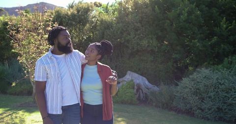 African american couple strolling arm-in-arm on sunlit garden lawn sharing warm affection