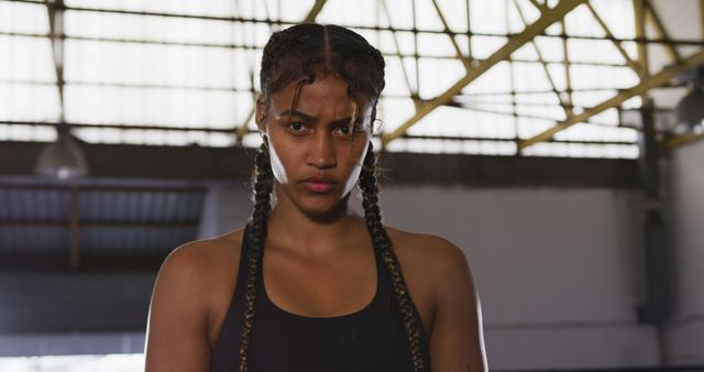 Portrait of confident biracial female boxer with braids at boxing club. Confidence, boxing, sport, strength and competition, unaltered.