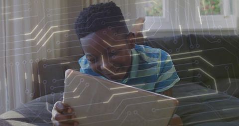 Smiling child using tablet on couch with circuit overlay for STEM learning and coding