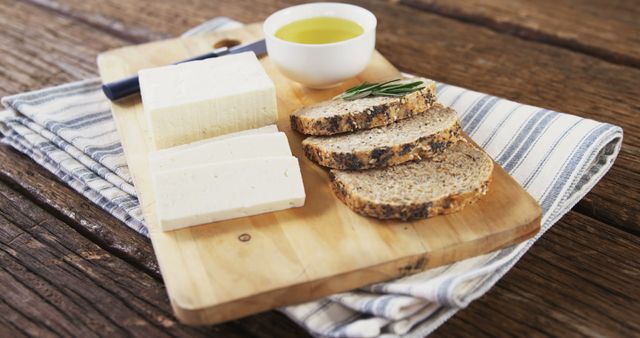 Slices of fresh tofu alongside rustic bread and olive oil present a simple, healthy meal option, with copy space. Tofu, a versatile soy-based protein, is a staple in vegetarian and vegan diets.