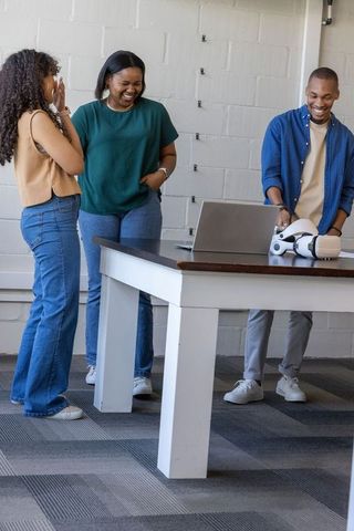 African american coworkers laughing while reviewing tech project with laptop and headset