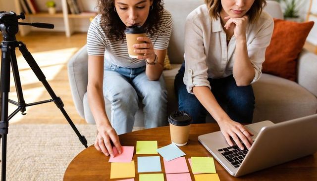 Creative team brainstorming with sticky notes and laptop in cozy home office