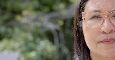 Sophisticated middle-aged woman with glasses in serene garden