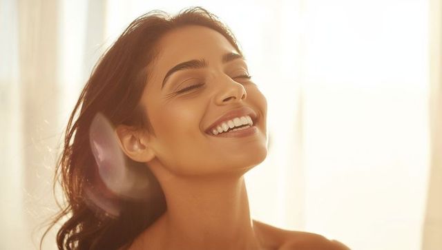 Joyful woman bathing in golden sunlight beneath shade