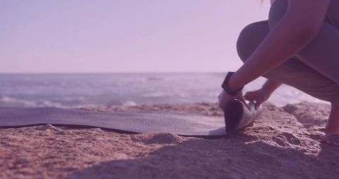 Woman Preparing Yoga Mat by Ocean for Outdoor Exercise