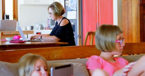 Children Engaged with Technology at Home While Mother Works