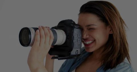 Female Photographer Smiling While Shooting with DSLR and White Telephoto Lens