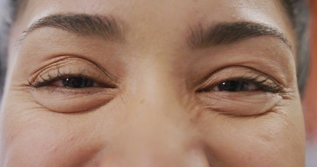 Close up portrait of eyes of happy biracial female doctor smiling and looking to camera. Medicine, healthcare, lifestyle and hospital concept.