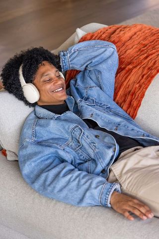 African american man reclining on gray sofa listening to music with white headphones