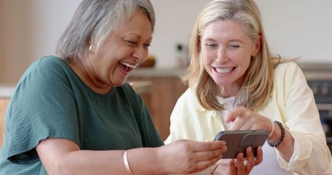 Smiling Mature Women Enjoying Social Media in Kitchen Setting