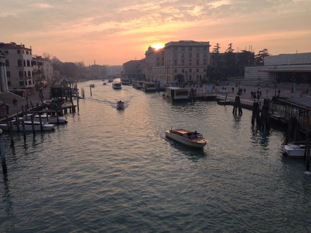 A beautiful evening view of Venice with boats sailing down the canal at sunset. The city architecture is visible along the edge of the water. This stock photo is ideal for travel blogs, tourism advertisements, and promotional materials for Venice or Italy. Suitable for web use or printed travel guides.