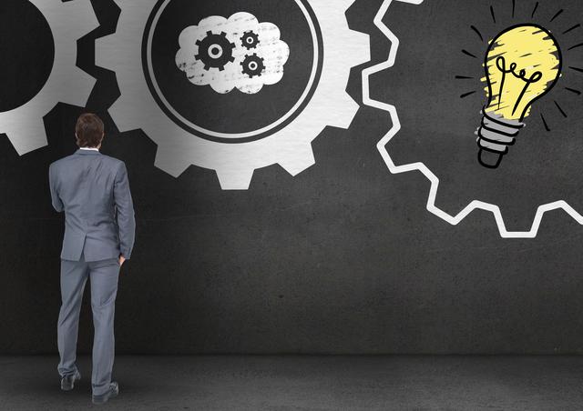 Businessman stands in front of a wall, analyzing illustrations of cogs and a glowing light bulb. Symbolizes innovation, strategic planning, and problem-solving. Suitable for use in business-related presentations, articles on innovation, and advertising campaigns targeting business solutions.