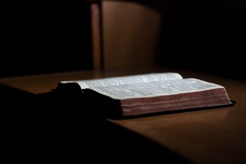 Open bible in dim light on wooden table