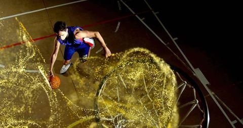 Dynamic basketball player jumping towards hoop with energetic golden trail