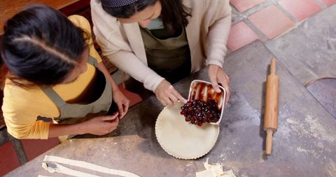 Student and mentor preparing cherry pie in rustic kitchen setting