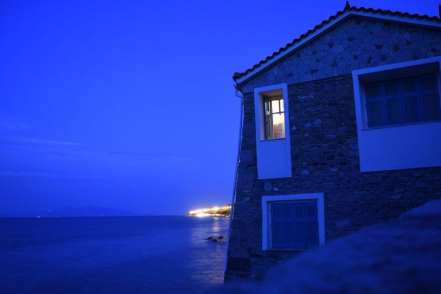 Cozy seaside house at night with warm interior light shining from window - Download Free Stock Images Pikwizard.com