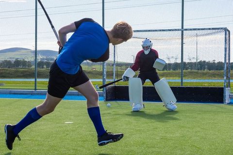 Field hockey players in intense game action on green turf