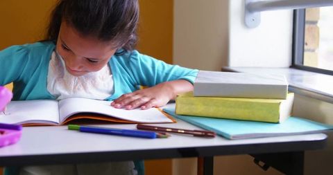 Young Girl Studying by Window in Bright Classroom Setting