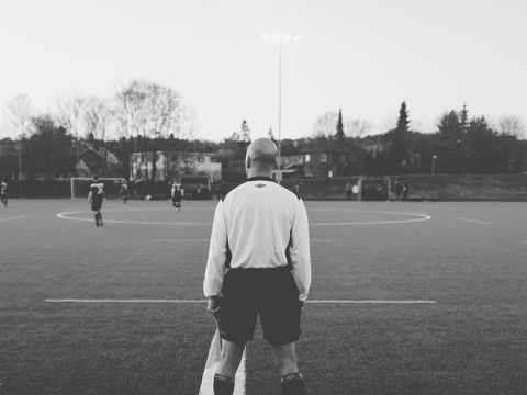 Black and white scene of soccer referee watching youth game