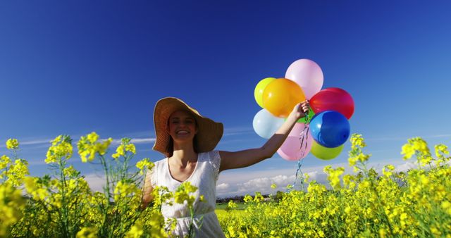 Joyful Woman Walking with Colorful Balloons in Sunny Mustard Field - Download Free Stock Images Pikwizard.com