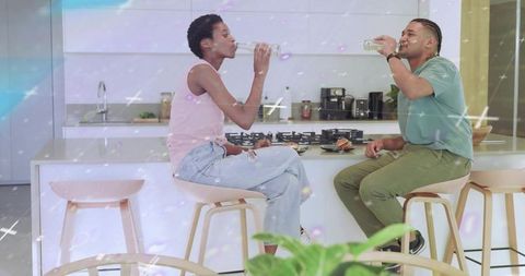 Friends drinking water at kitchen island sharing laughs in modern minimal home interior