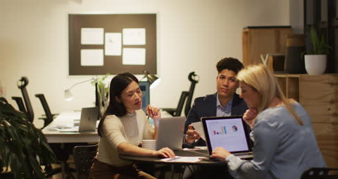 Diverse Collaborators Working on Project in Dim Office Environment