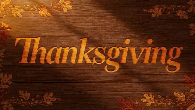 Thanksgiving lettering carving into wooden plank with autumn leaves and warm golden glow